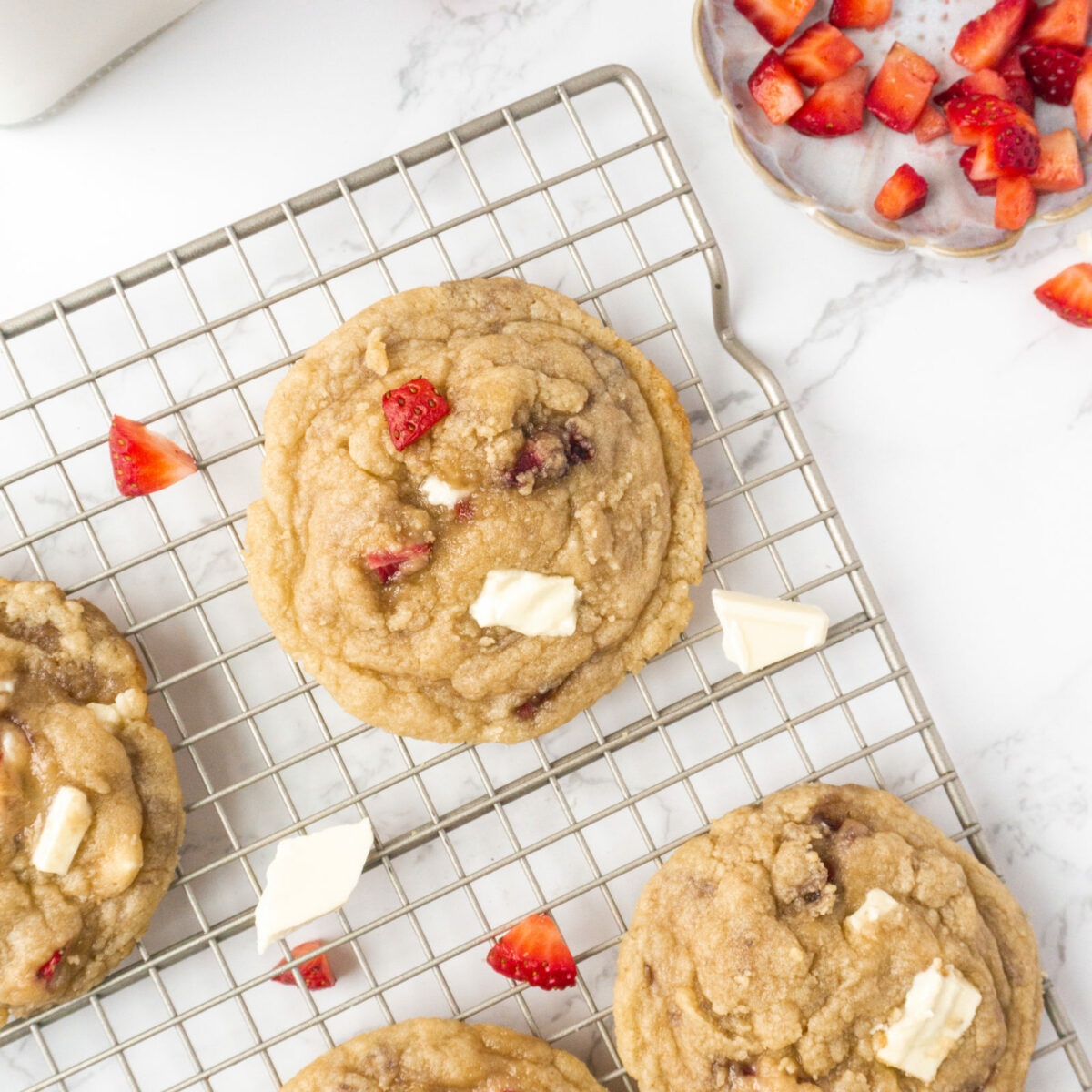An overhead view of fresh strawberry white chocolate chip cookies on a wire cooling rack. 