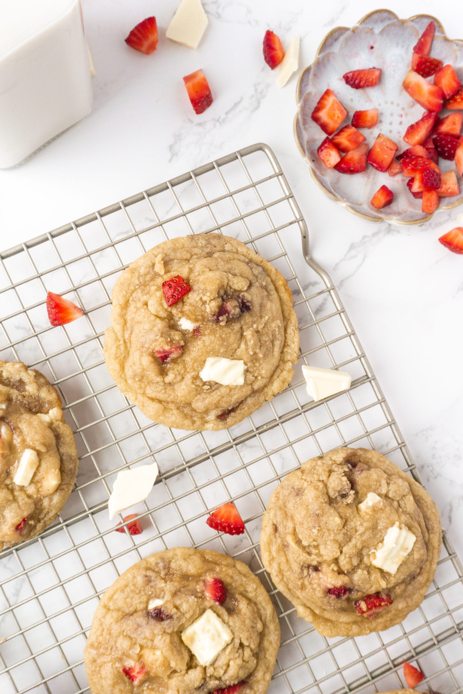 An overhead view of fresh strawberry white chocolate chip cookies on a wire cooling rack. 