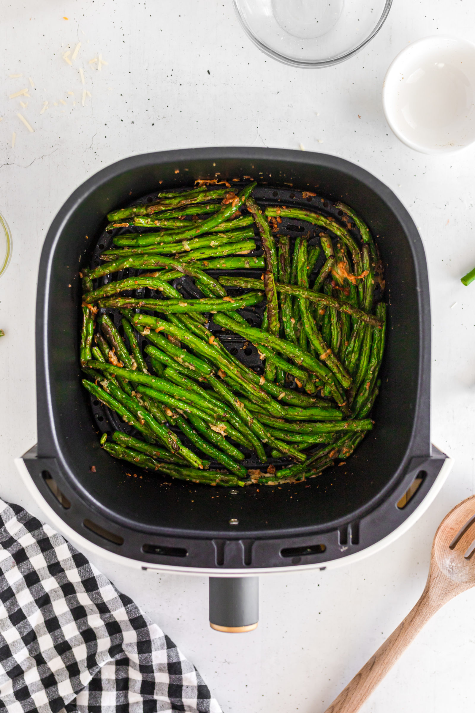 Overhead view of fresh green beans with parmesan in an air fryer. 