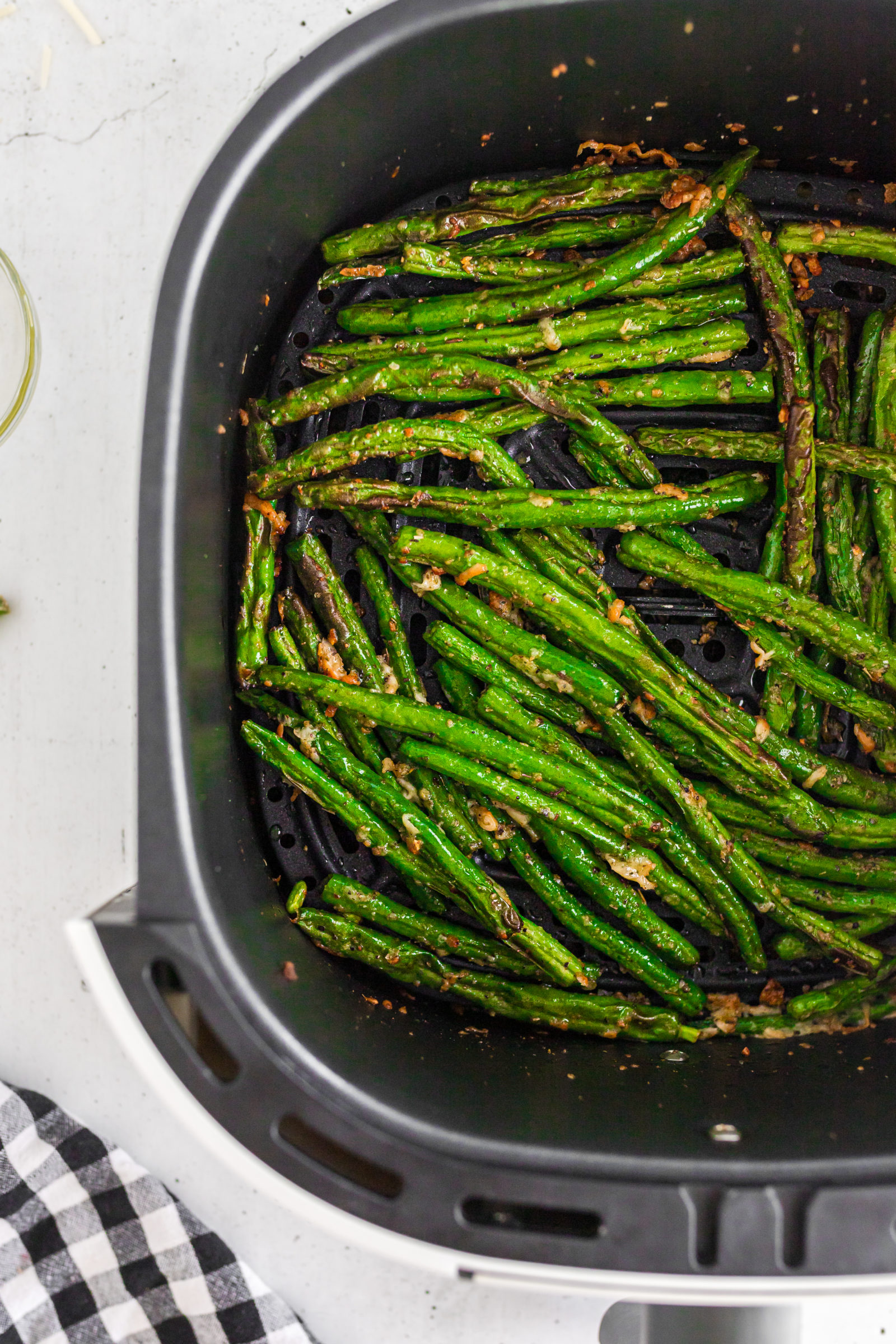 An overhead view of fresh green beans in an air fryer. 