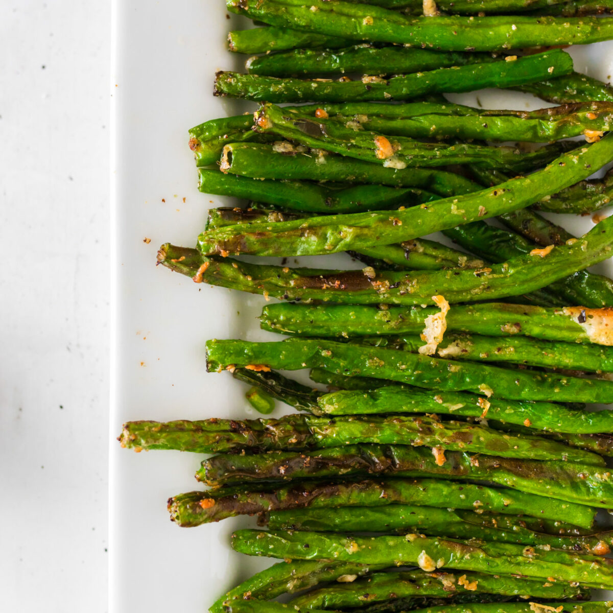 Overhead view of air fryer parmesan green beans on a white platter.