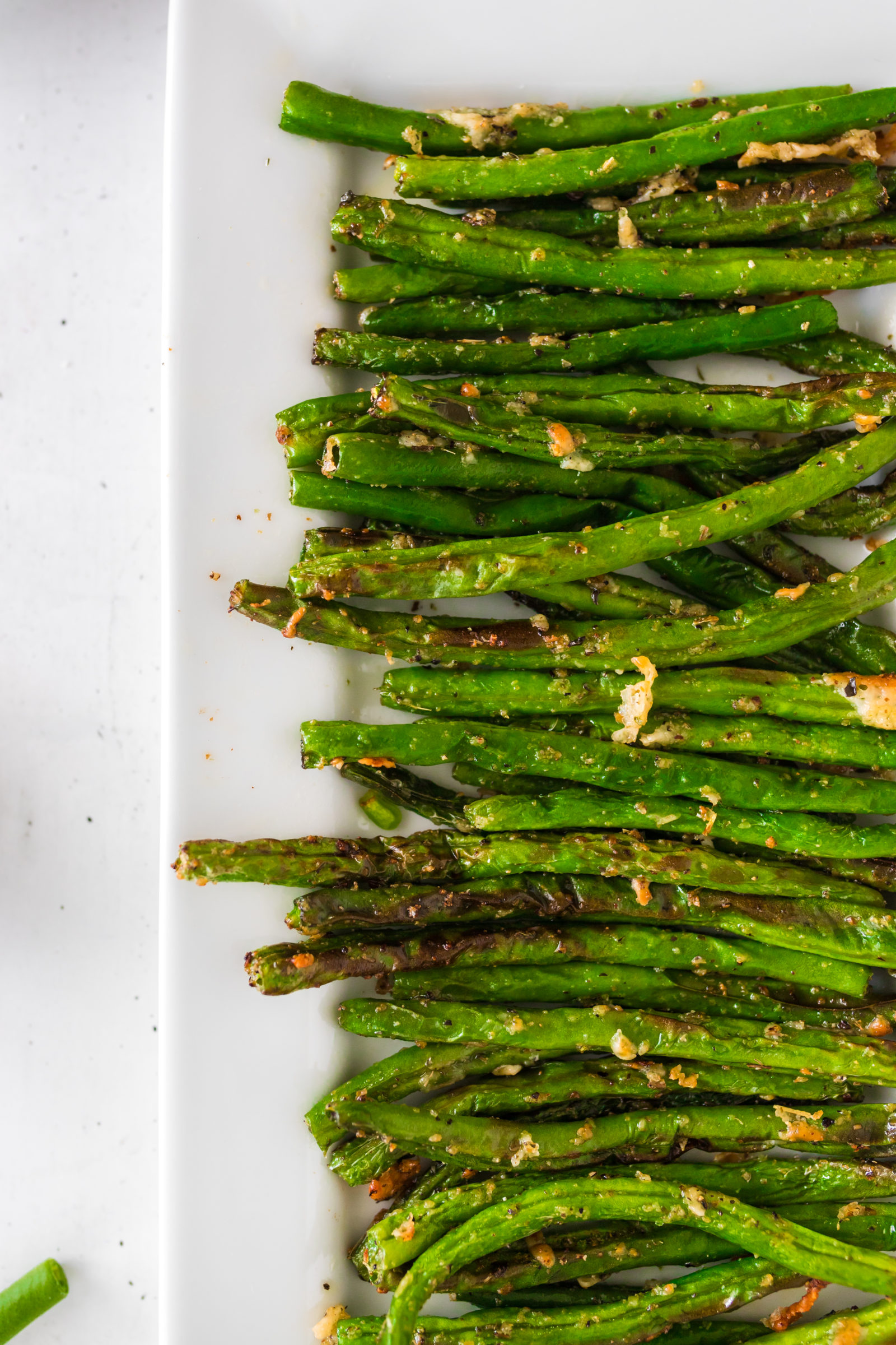 Overhead view of air fryer parmesan green beans on a white platter. 