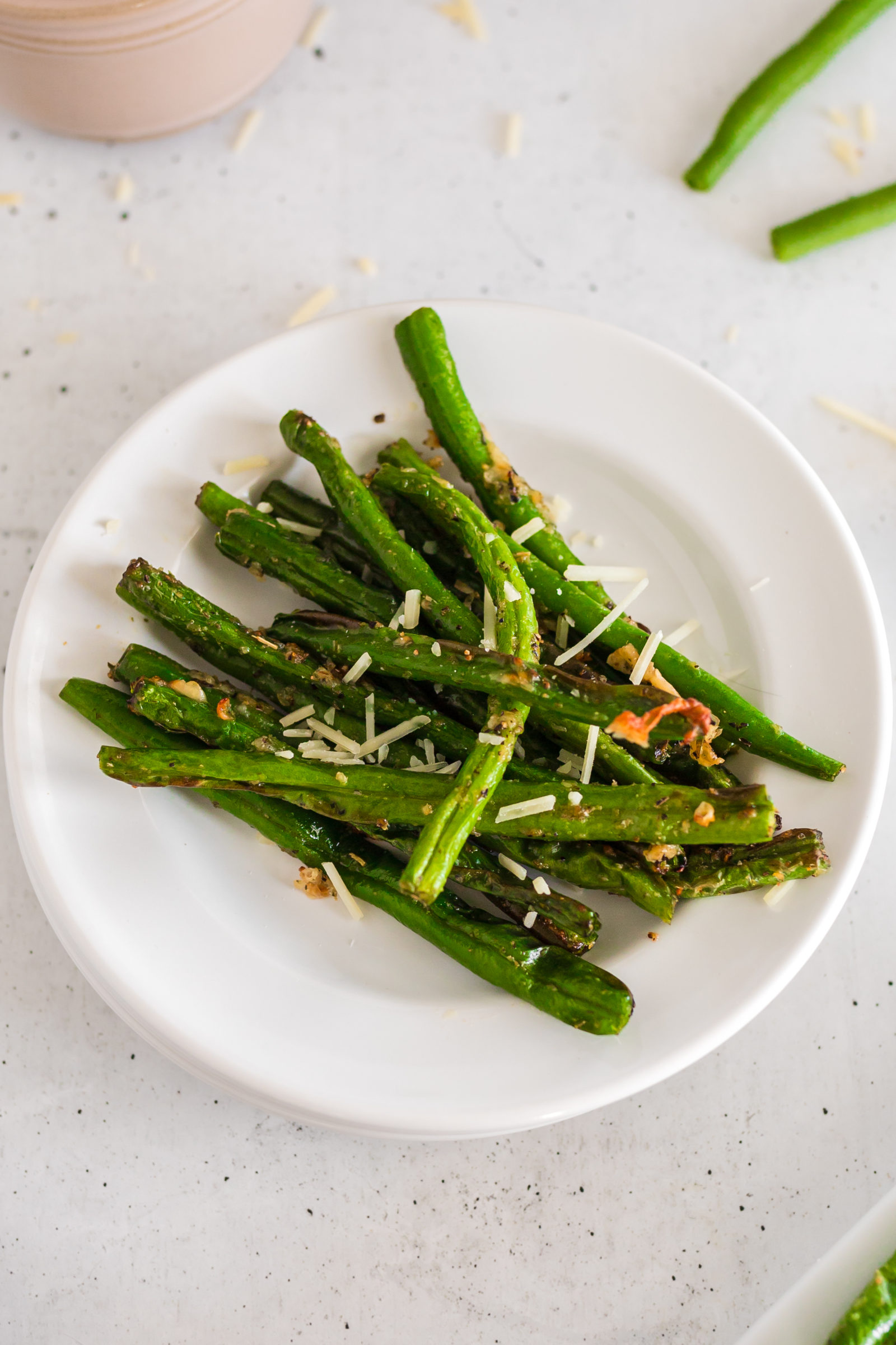 A serving of air fryer parmesan green beans on a white plate. 