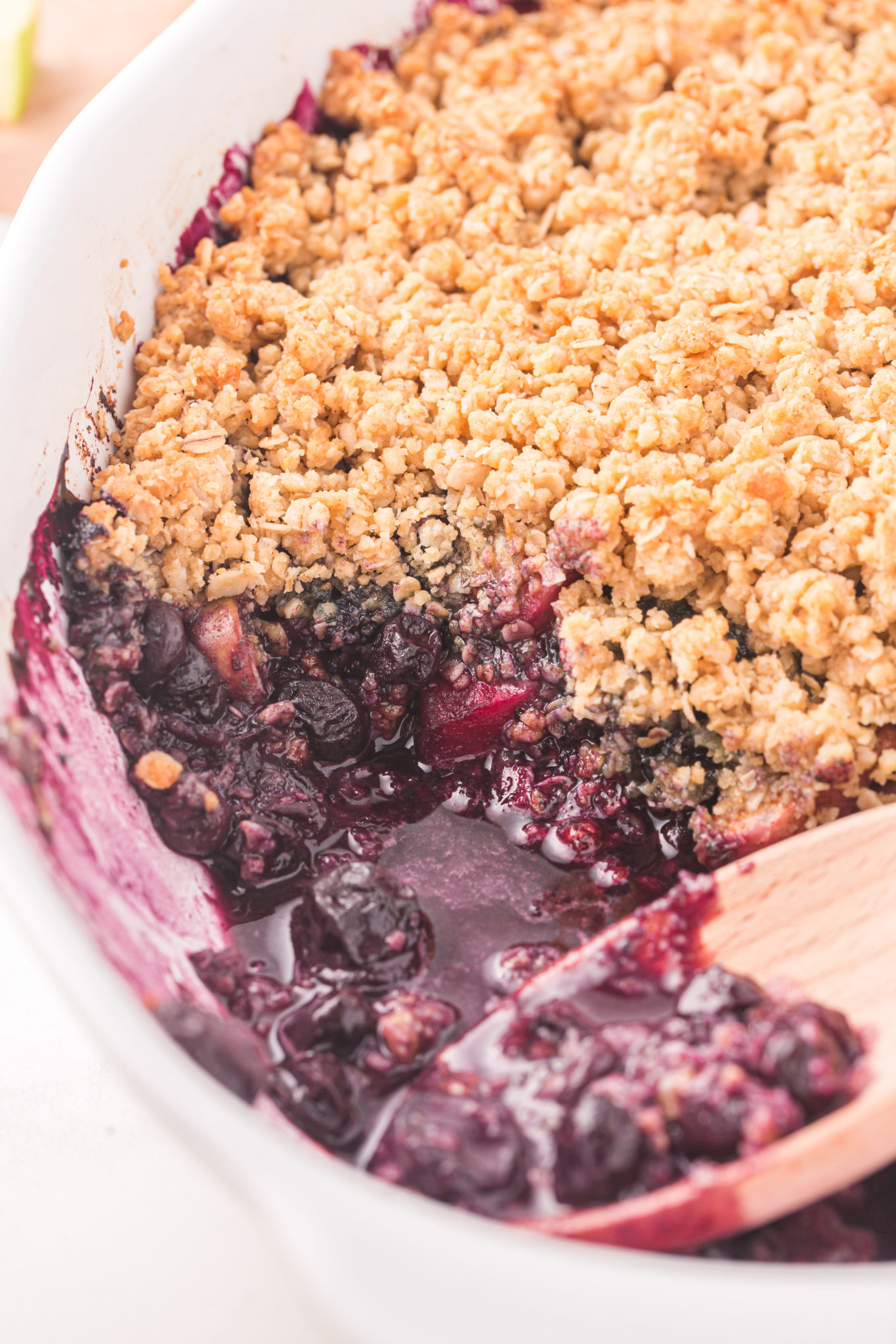 Apple blueberry crumble in a baking dish, with a serving missing.