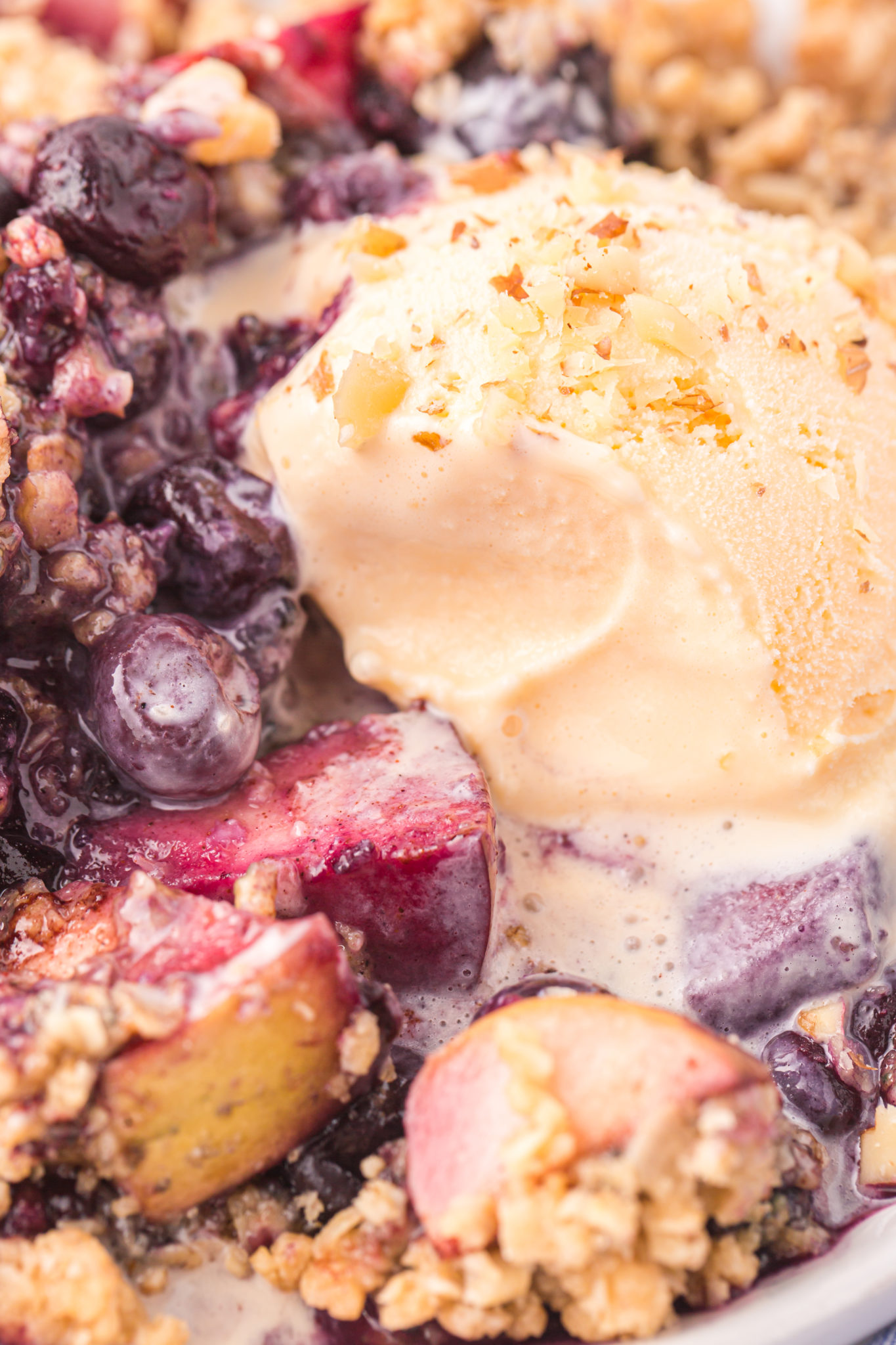 A close up view of apple blueberry crumble a la mode.
