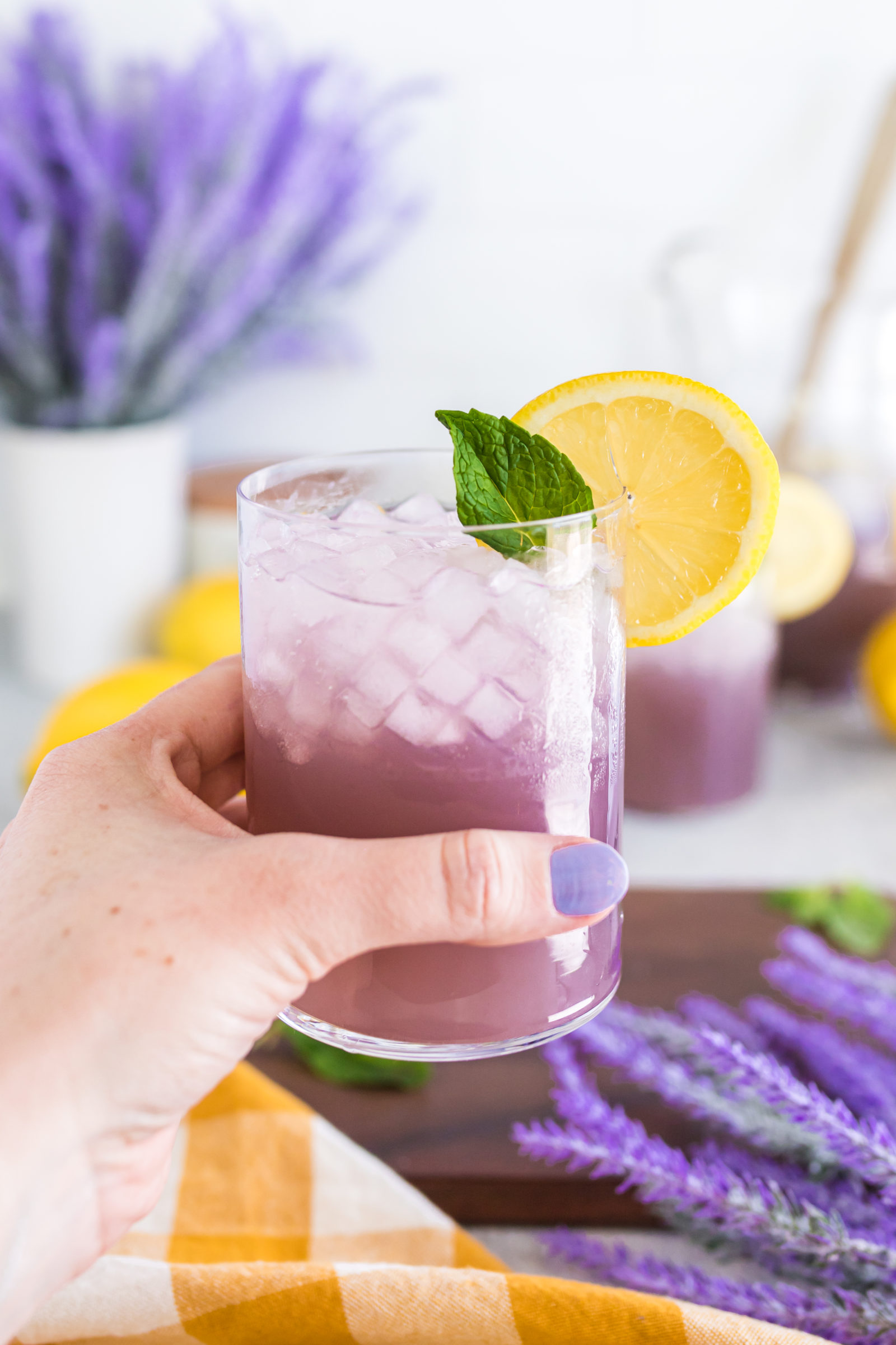 hand holding a clear glass of lemonade