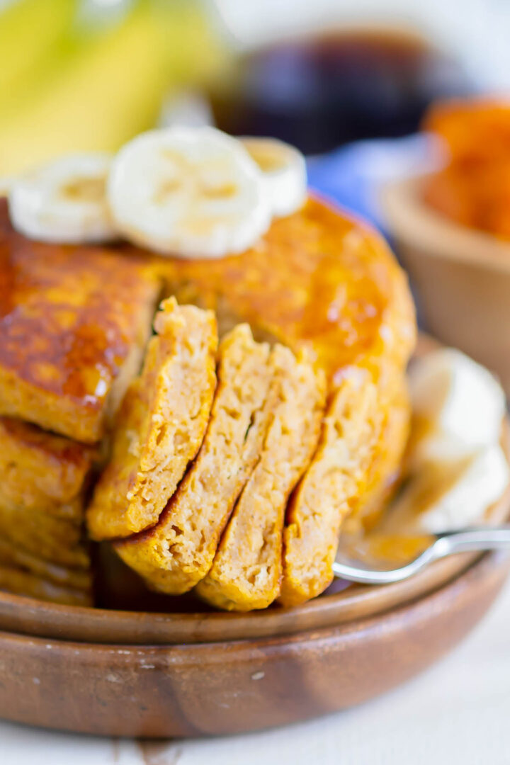 stack of pancakes with a forkful of pancake bites on a wooden plate