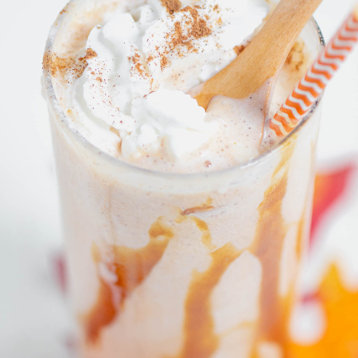 pumpkin shake in a clear glass with a wooden spoon