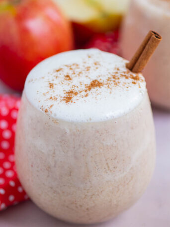 smoothie in a short glass with whipped cream and a cinnamon stick