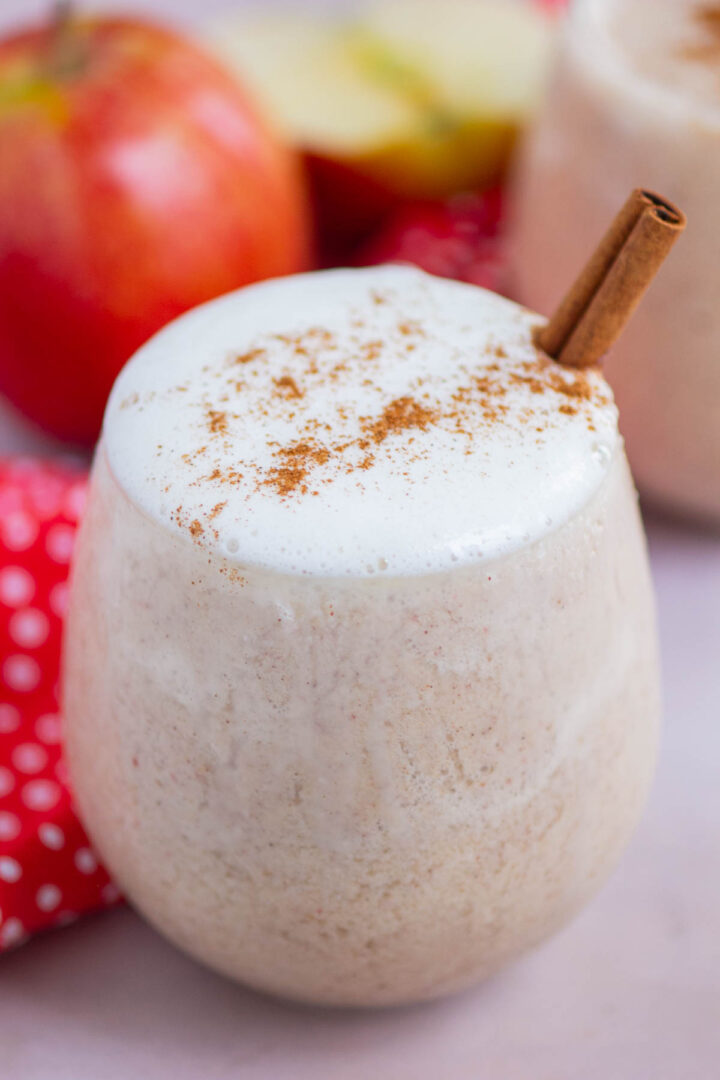 smoothie in a short glass with whipped cream and a cinnamon stick