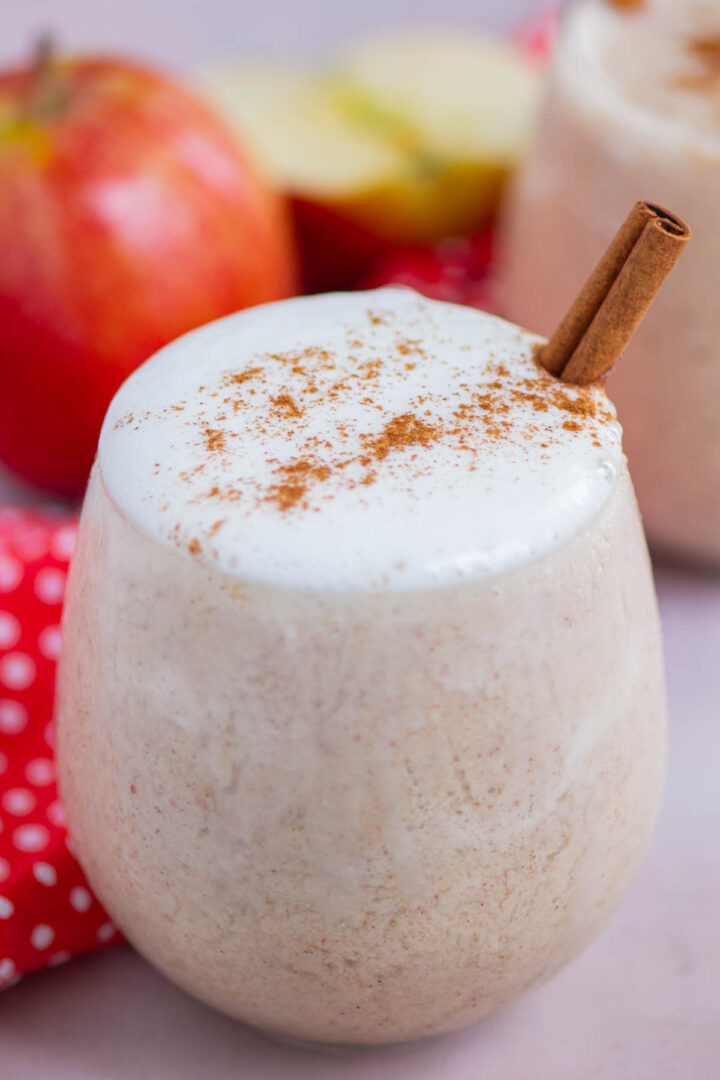 smoothie in a short glass with whipped cream and cinnamon stick