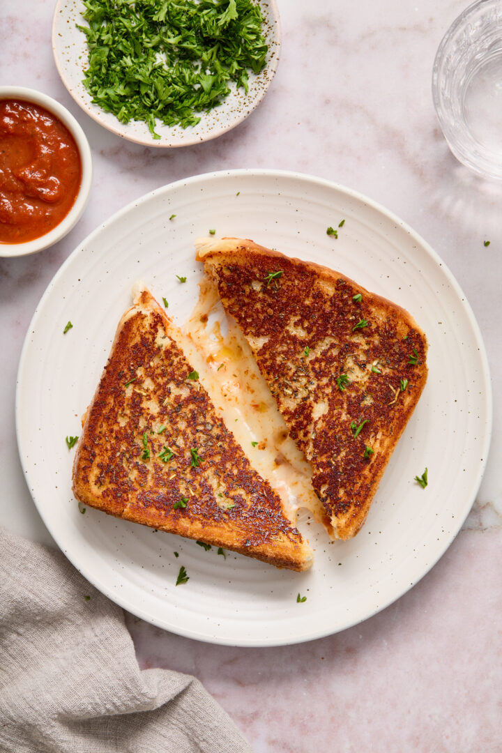 grilled cheese cut in half on a white plate