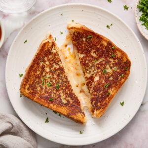 grilled cheese cut in half on a white plate