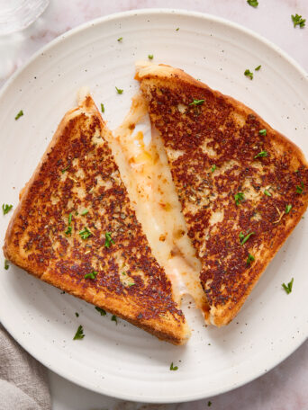 grilled cheese cut in half on a white plate