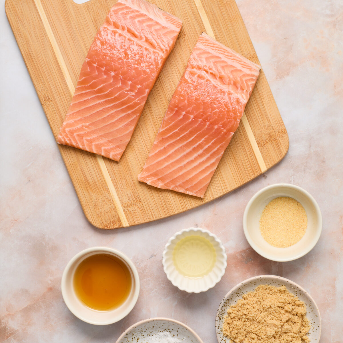 ingredient on a brown cutting board and light pink surface
