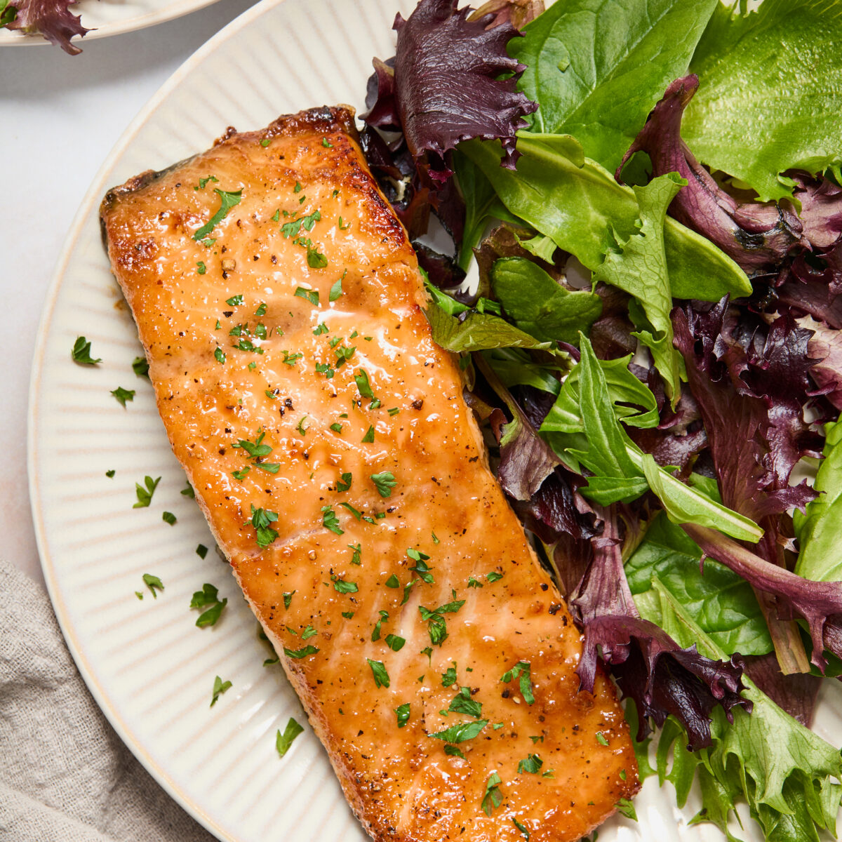 salmon and green lettuce on a white plate