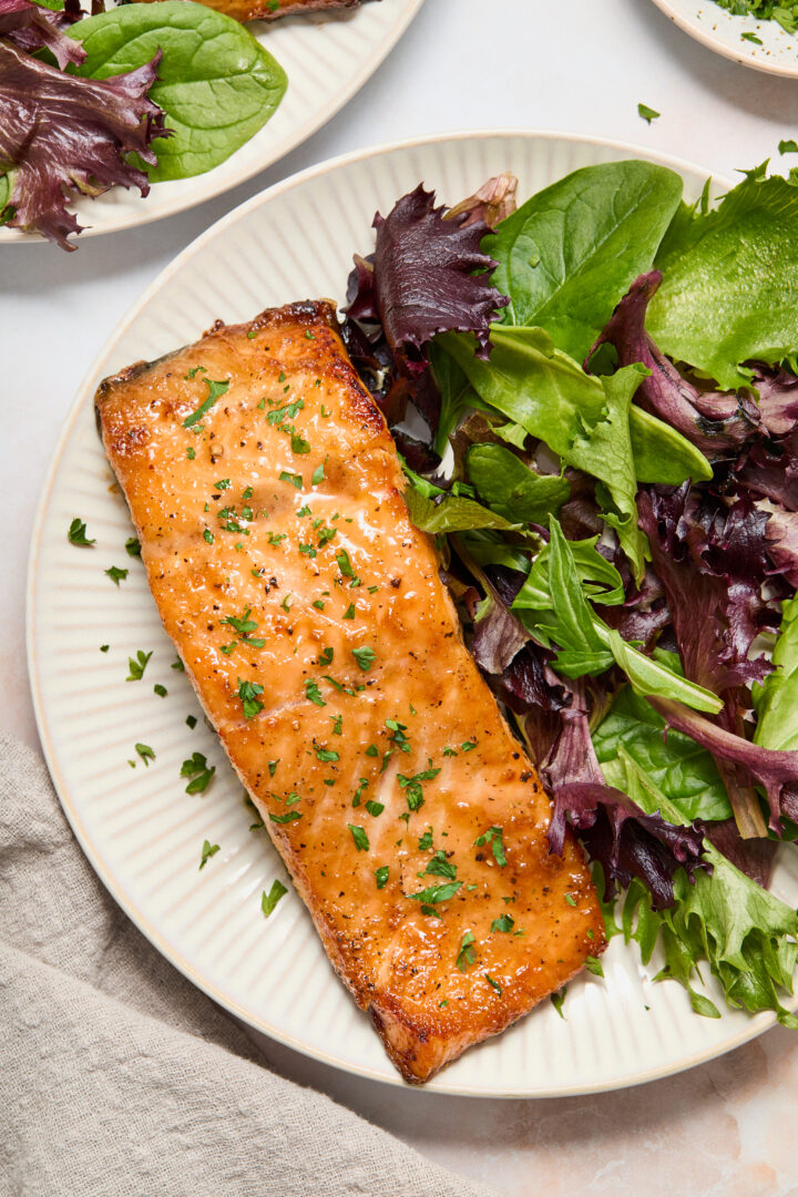 salmon and green lettuce on a white plate