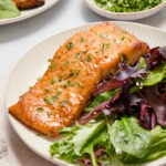 salmon and green lettuce on a white plate