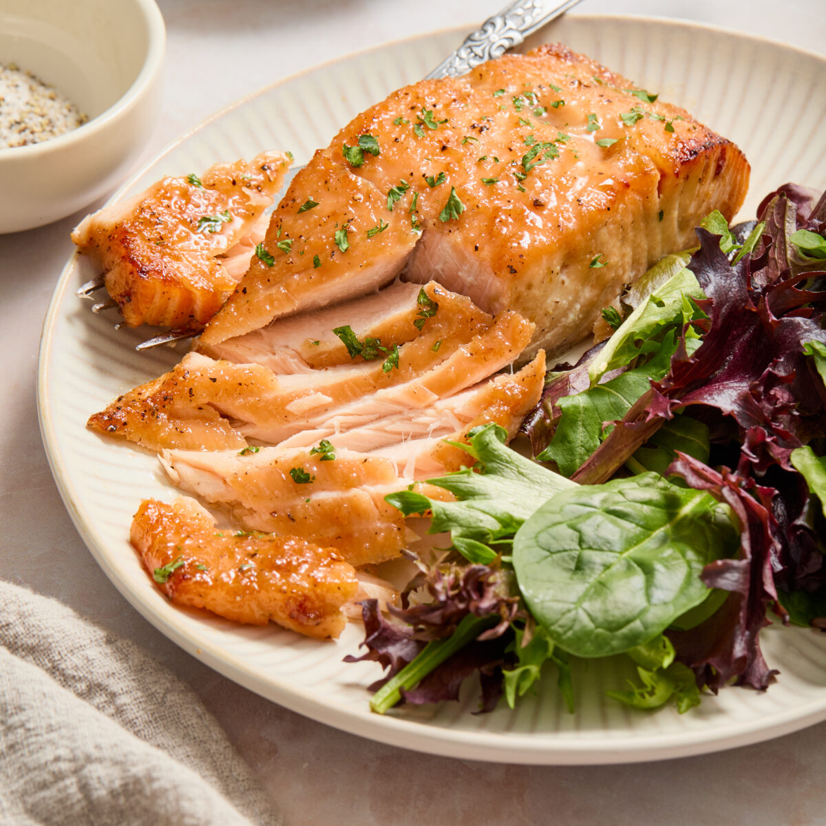 salmon flaked with a fork and green lettuce on a white plate