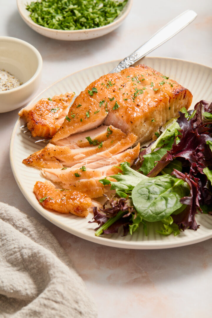 salmon flaked with a fork and green lettuce on a white plate