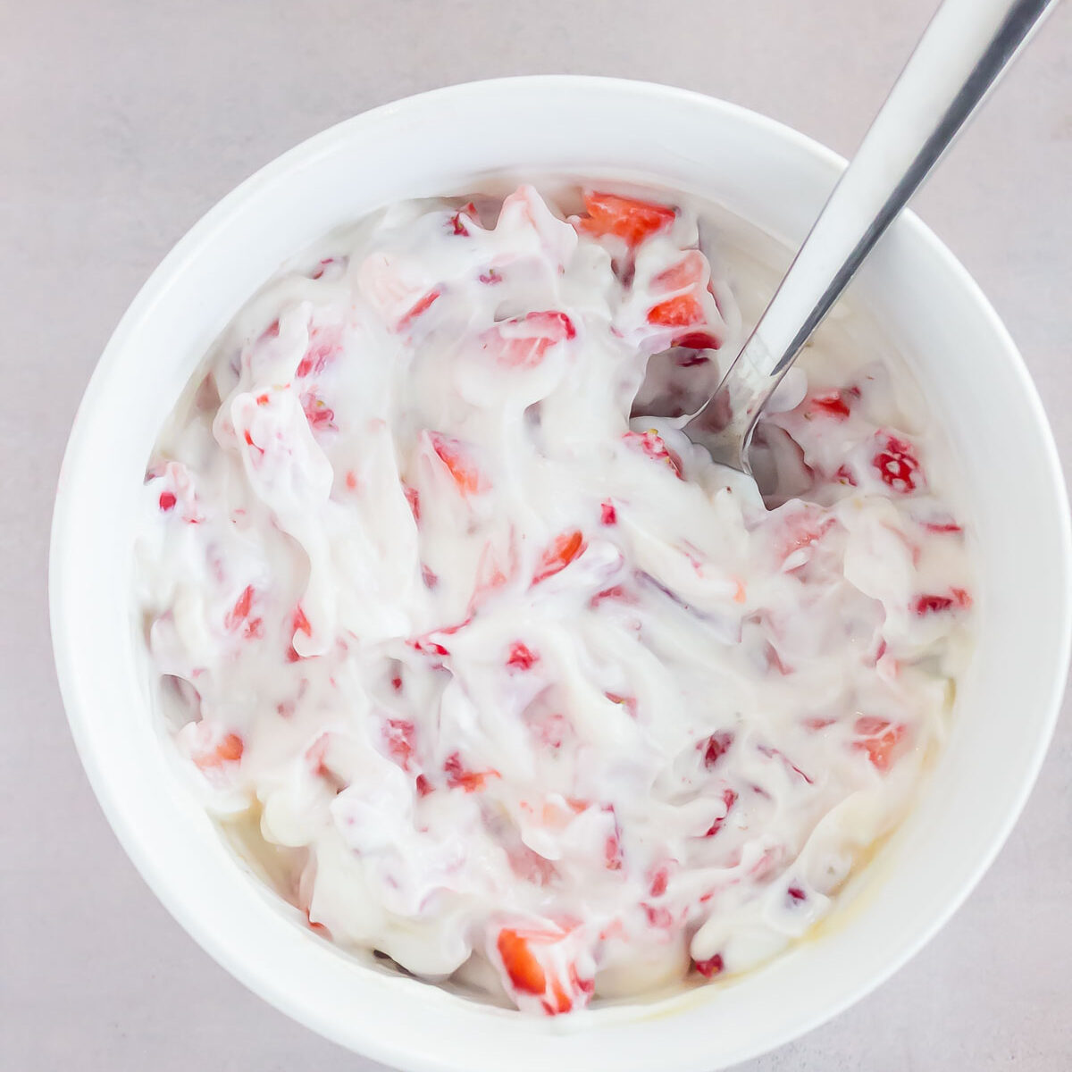 yogurt mixture in a white bowl with a metal spoon