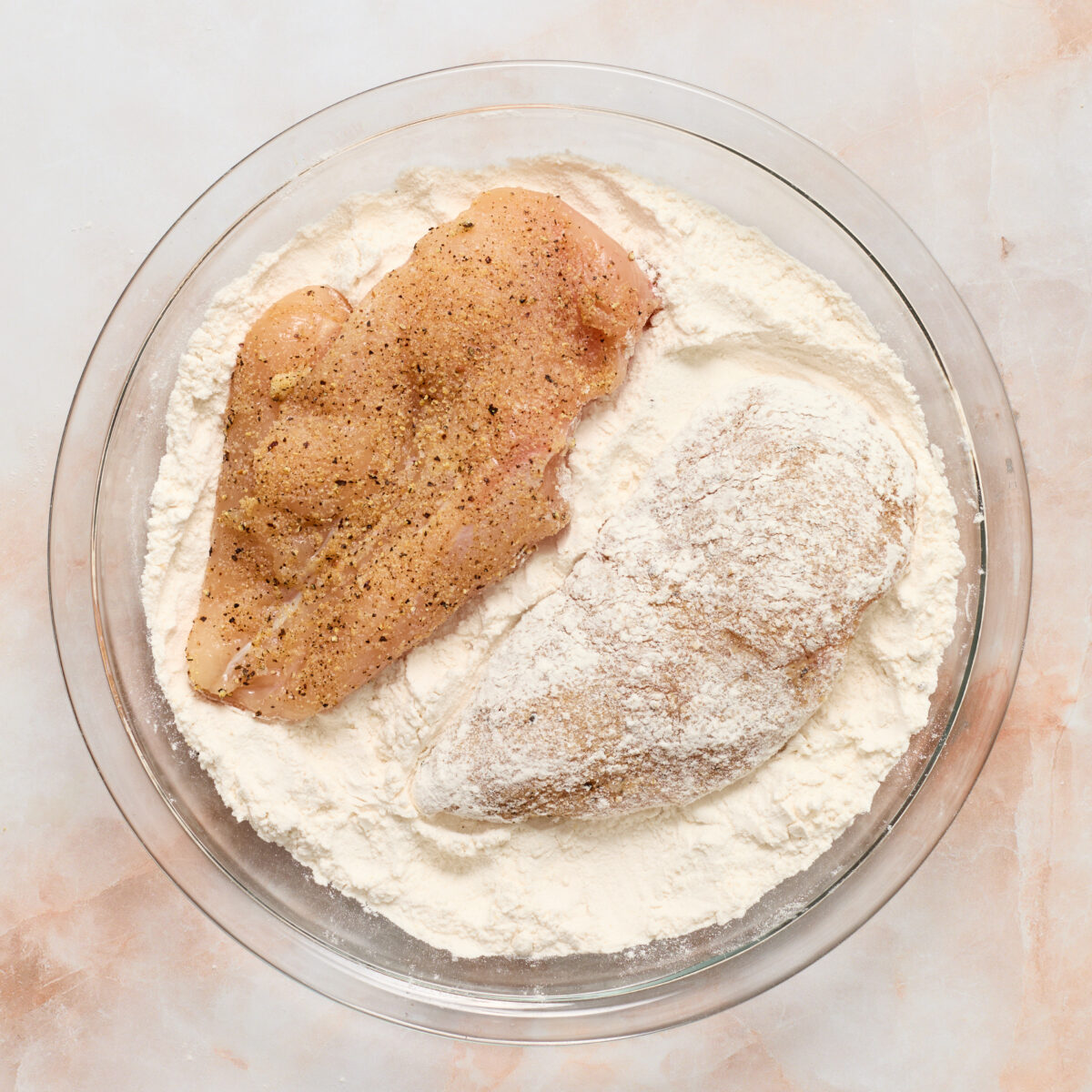 chicken in a glass bowl with flour