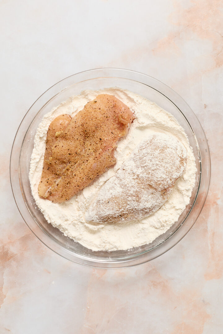 chicken in a glass bowl with flour