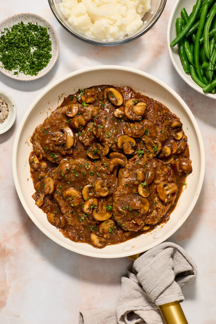 cube steak and mushroom gravy in a white pan