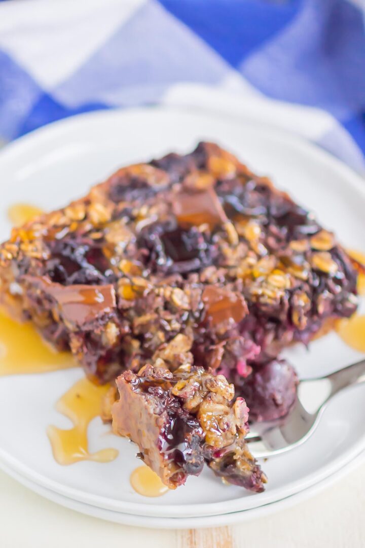 oatmeal slice on a white plate with a drizzle of honey and a bite on a silver fork