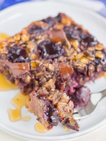 oatmeal slice on a white plate with a drizzle of honey and a bite on a silver fork