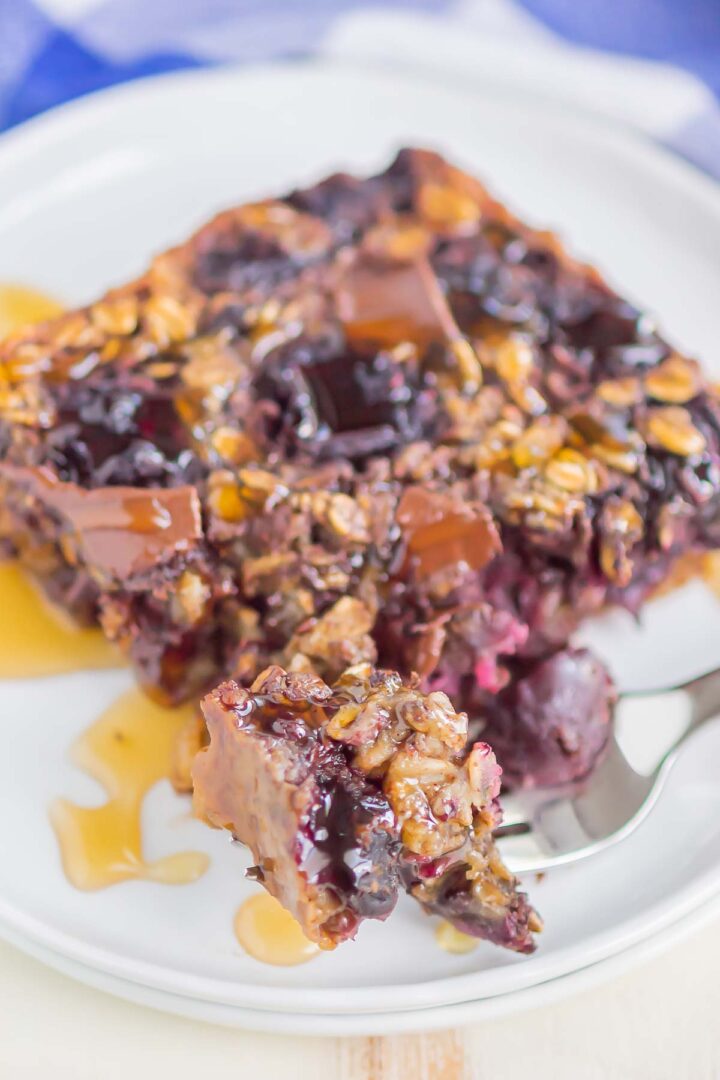 oatmeal slice on a white plate with a drizzle of honey and a bite on a silver fork