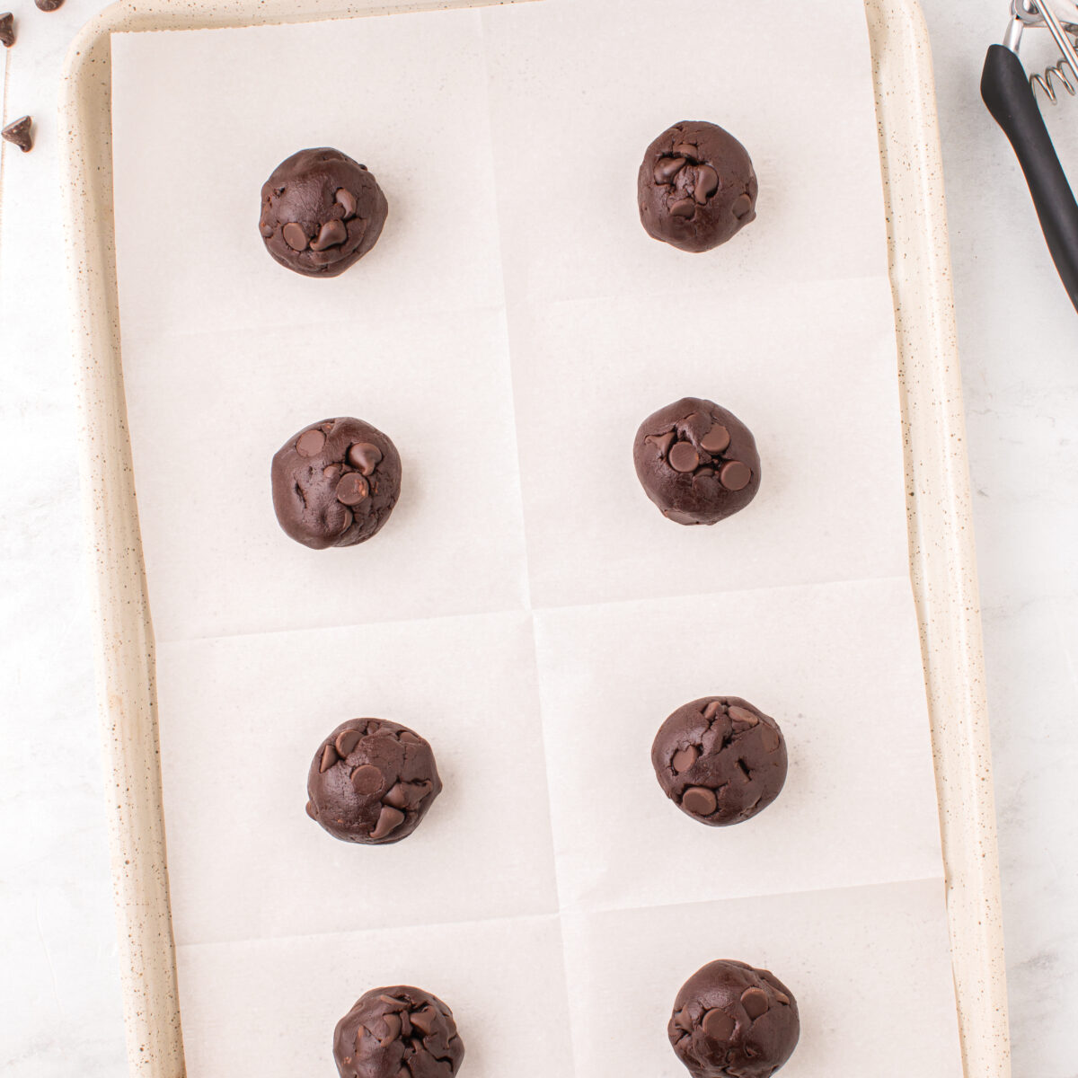 cookie batter scooped onto a parchment paper-lined pan
