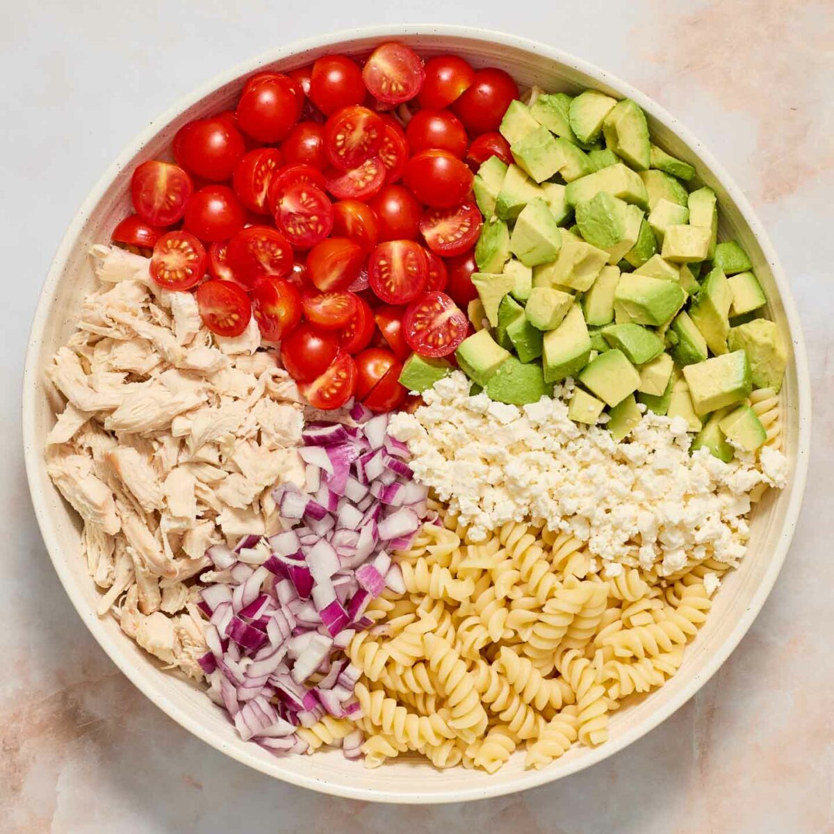 pasta salad ingredients in a white bowl