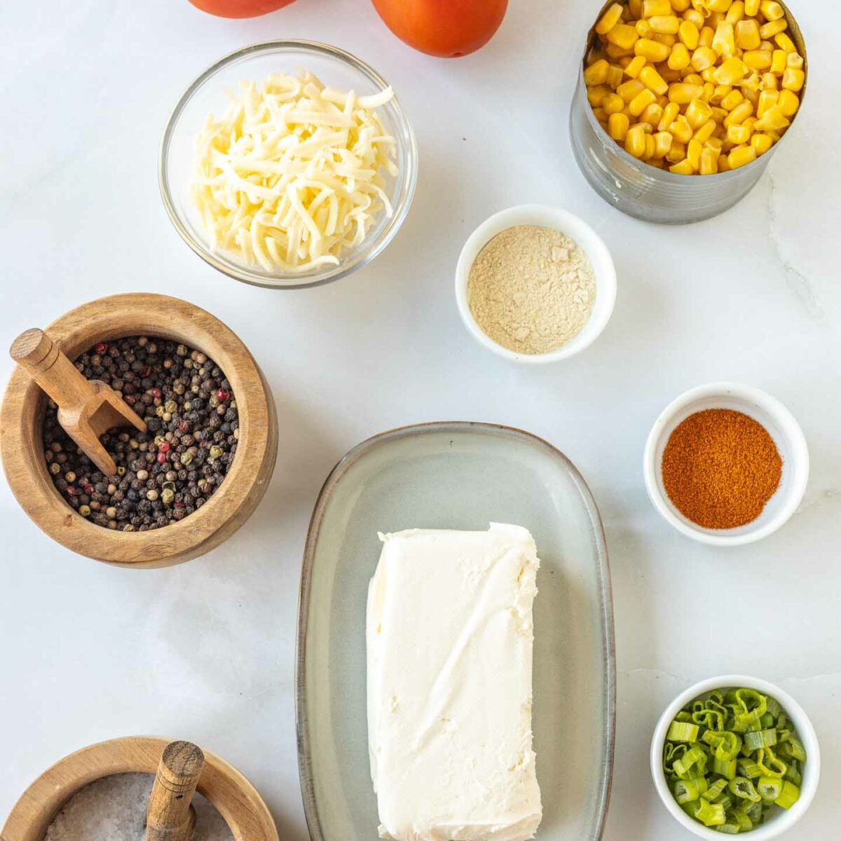 corn dip ingredients in small bowls on a white surface