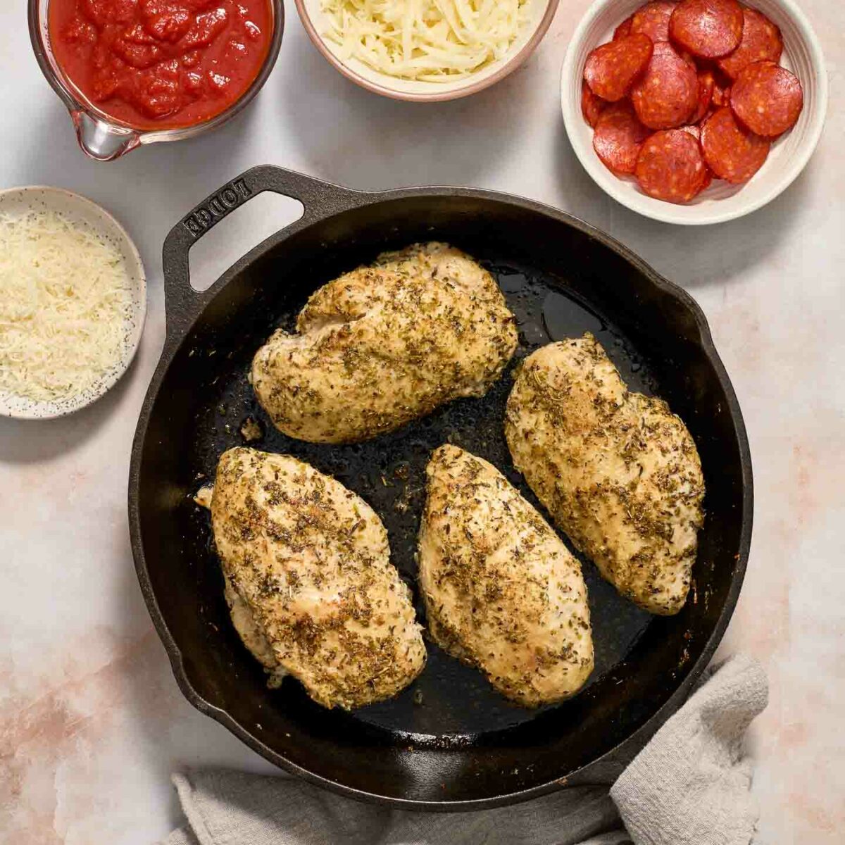 chicken seasoned in a black skillet with ingredients on the side