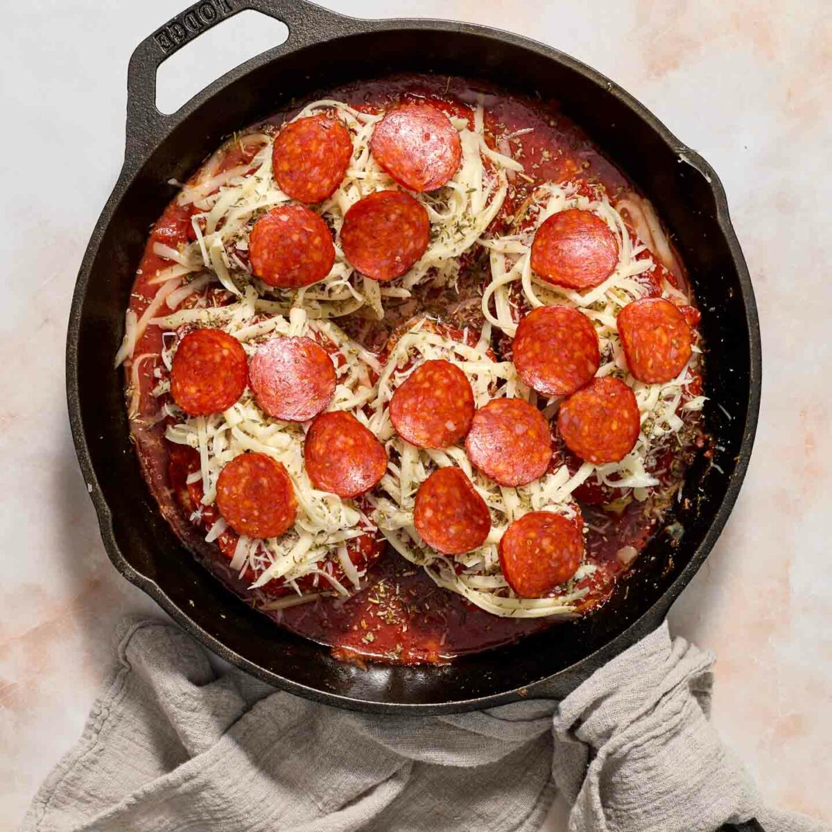 chicken in a black skillet with pepperoni and sauce