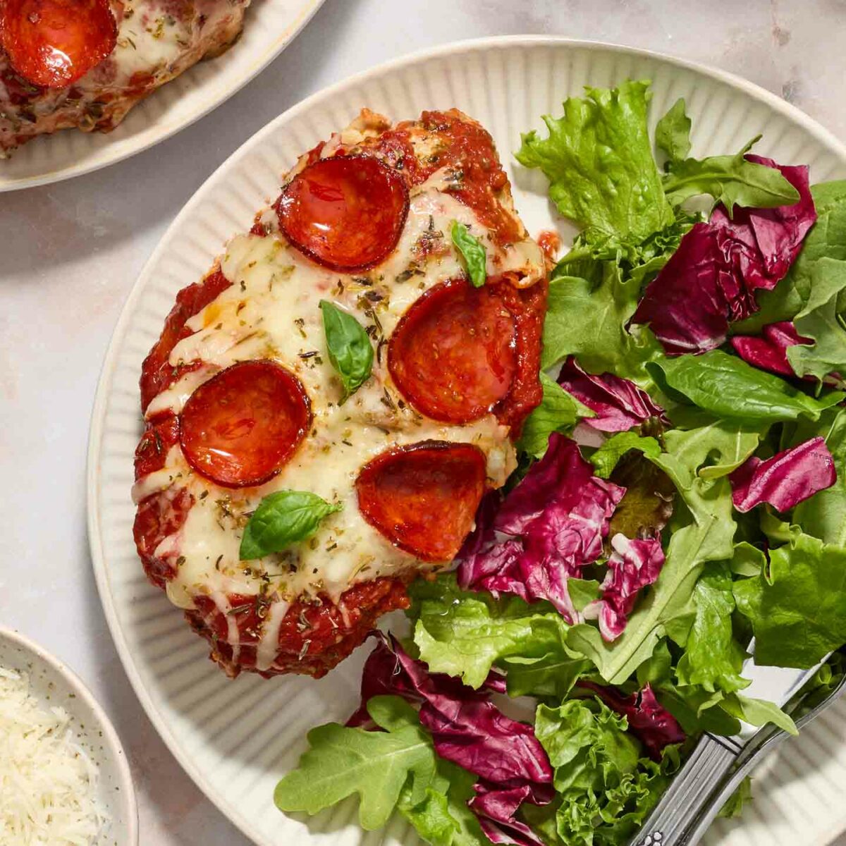 pizza chicken on a white plate with a green salad