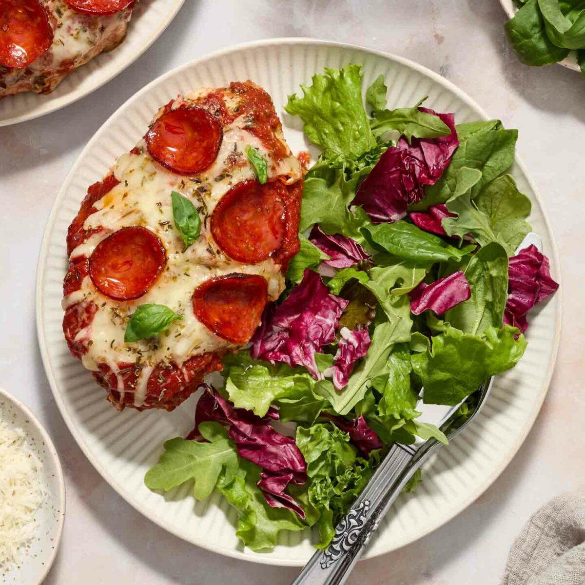 pizza chicken on a white plate with a green salad