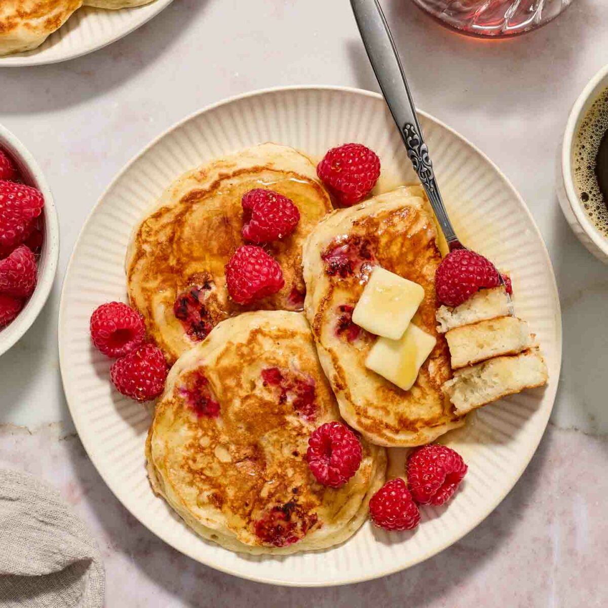 pancakes on a white plate with a bite of pancakes on a fork