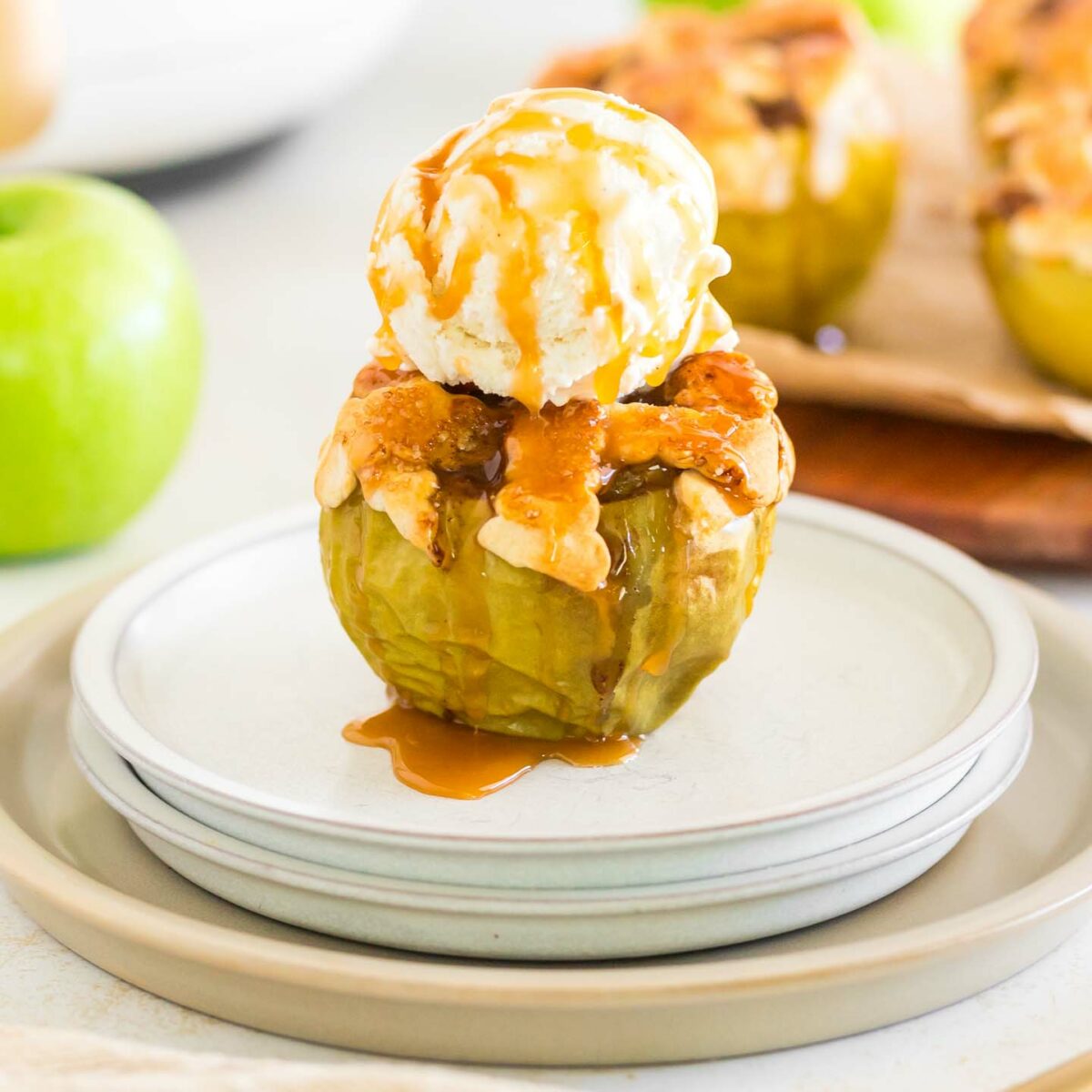 a baked apple with vanilla ice cream and caramel drizzle on a white plate