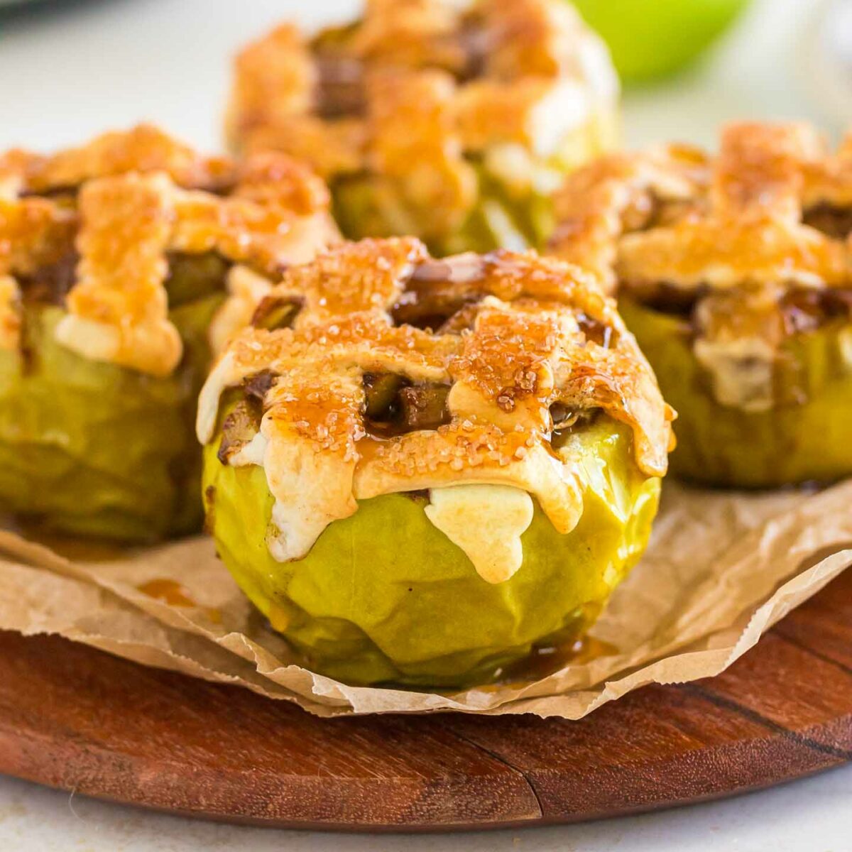 four baked apples on a wooden board
