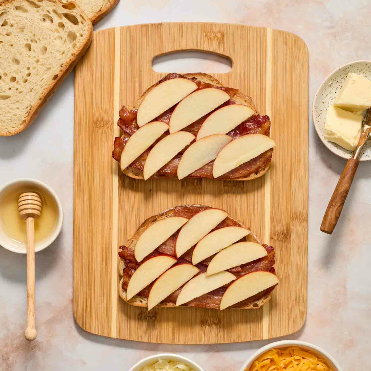 bread slices with bacon, honey, and apples on a cutting board