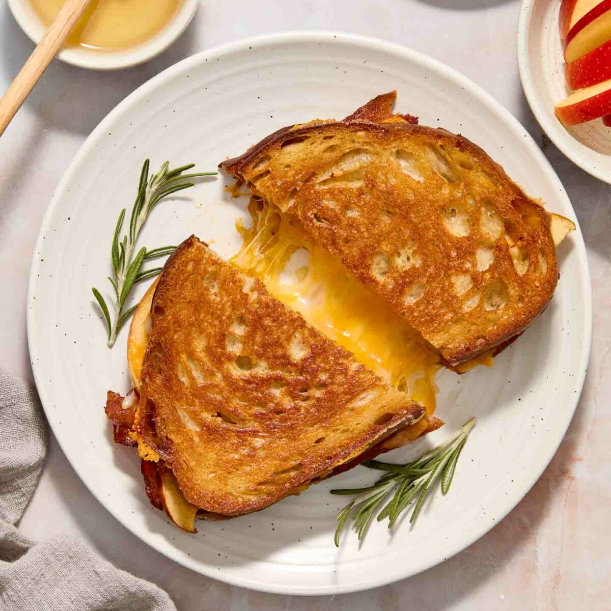 grilled cheese cut in half on a white plate with cheese oozing out