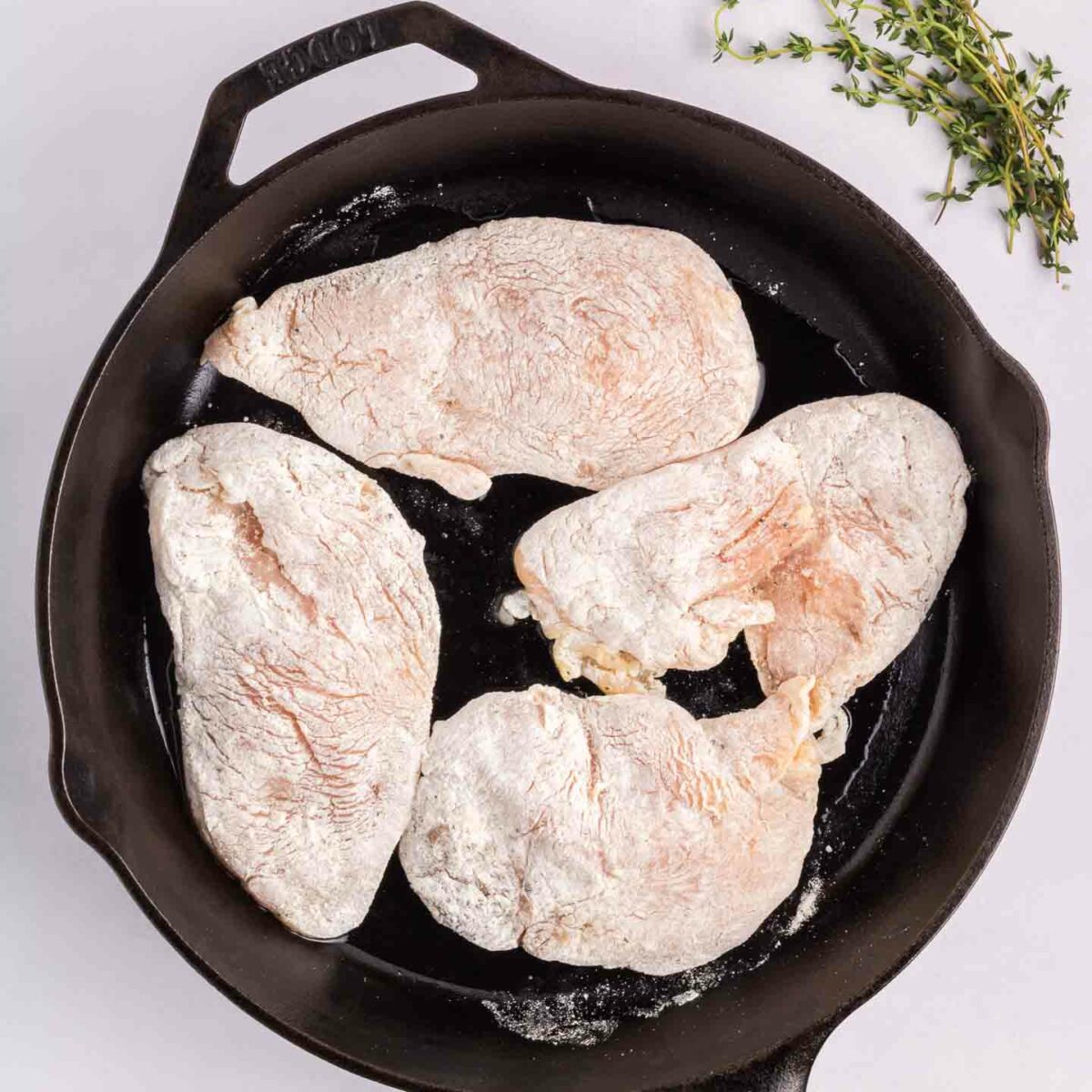 chicken coated in flour mixture in a black skillet
