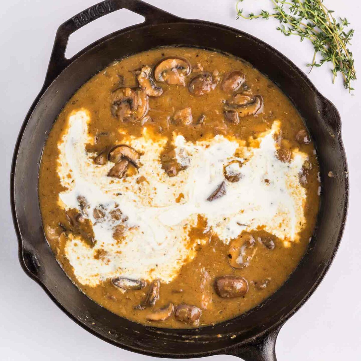 mushrooms, gravy and heavy cream in black skillet