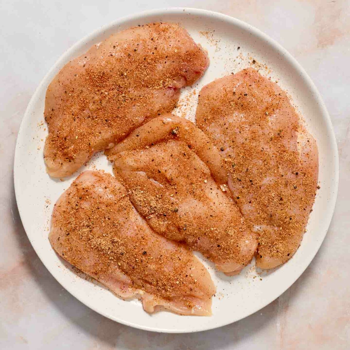 seasoned raw chicken on a white plate