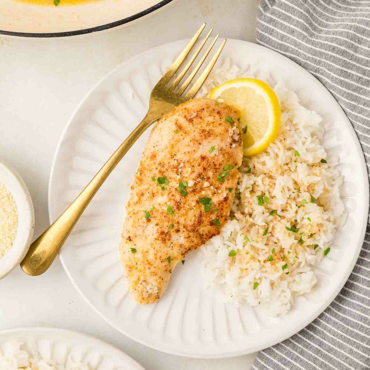 chicken on a white plate with rice and a fork