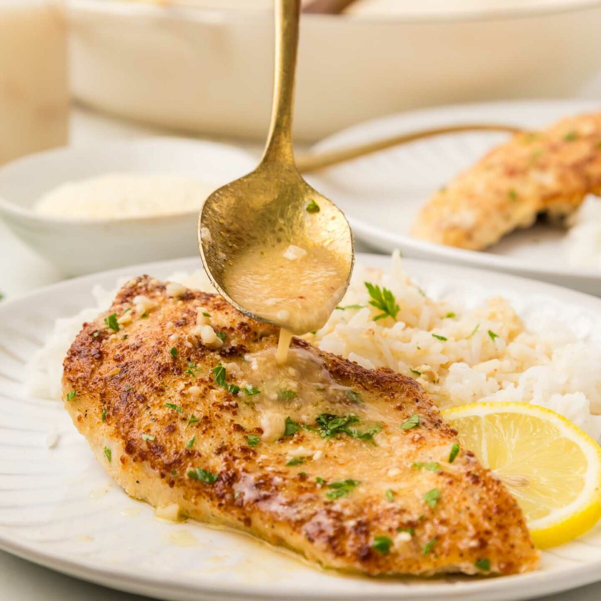 chicken on a white plate with rice and a spoon shown drizzling sauce over chicken