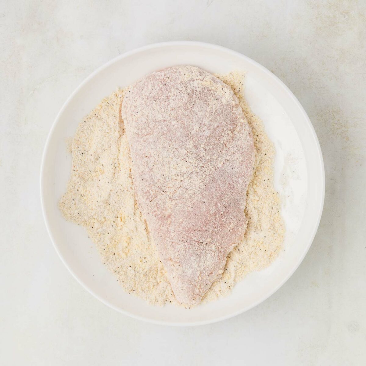 chicken dredged in flour mixture in a white dish
