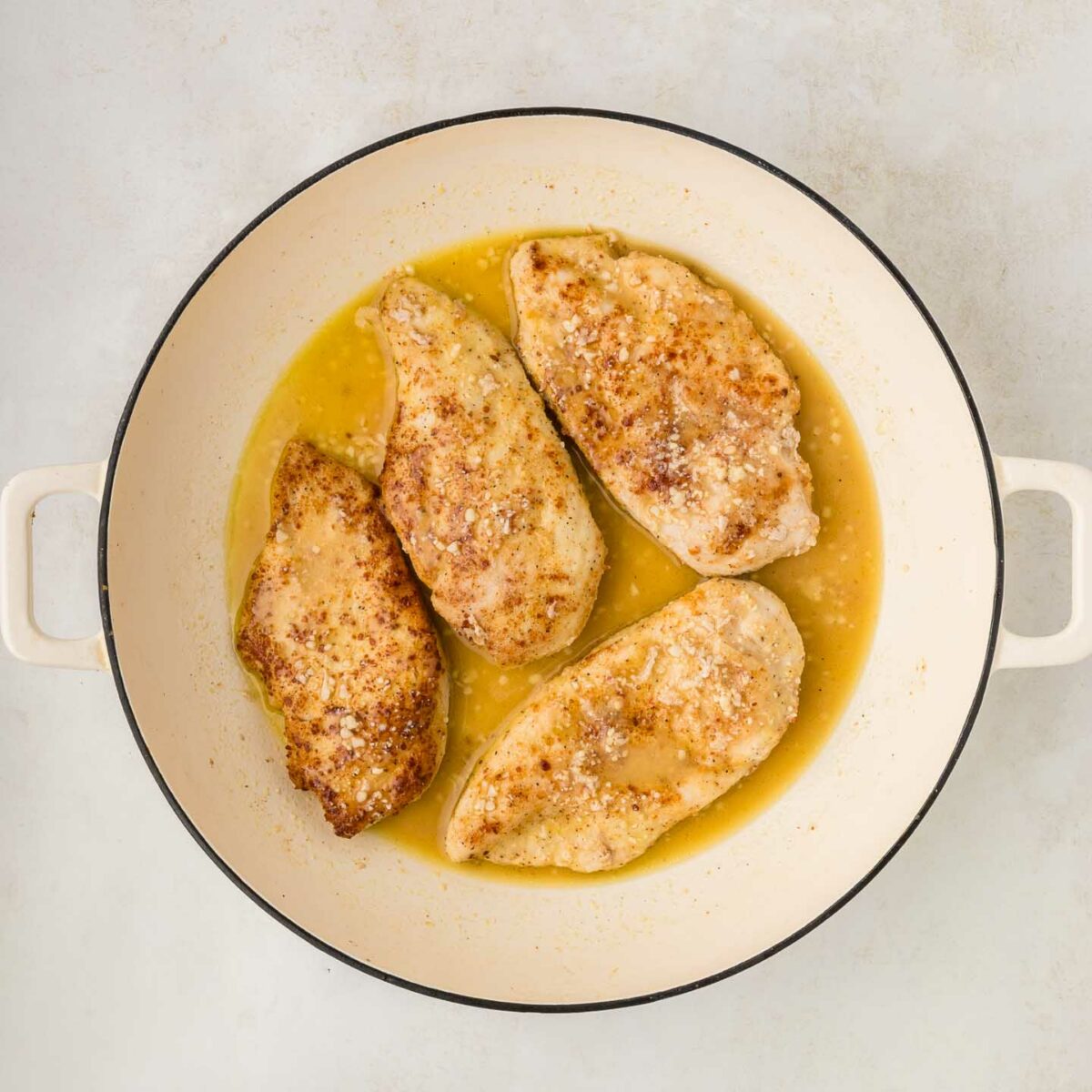 cooked chicken with the sauce in a white skillet